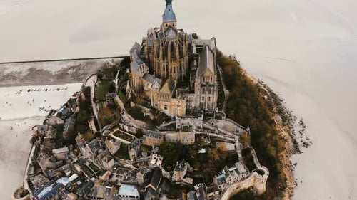 Drone Rises, Tilts Down on Mont Saint Michel, Ancient Island Fortress Town During Low Tide, World