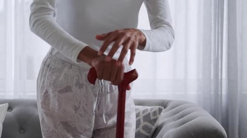 Senior Woman Resting Hands on Cane in Living Room
