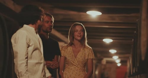 Friends Talking in Wine Cellar Near Wine Barrels