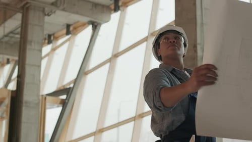 Woman Reviews Construction Blueprint on Site