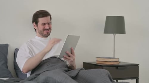 Man in Bed Expressing Frustration Using Tablet