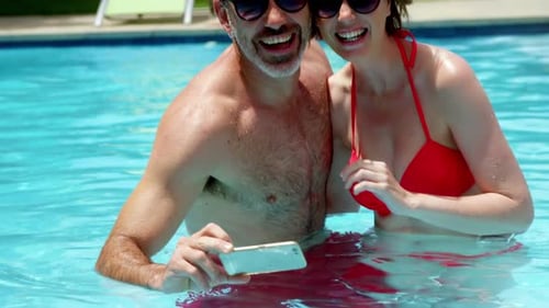 Couple taking a selfie on mobile phone in swimming pool