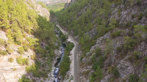A Man Stands Next To a Car in Road a Wild Mountain Gorge with a River in Turkey