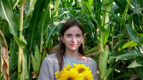 Femme aux tournesols Boquet posant et souriant entre de grands champs de maïs