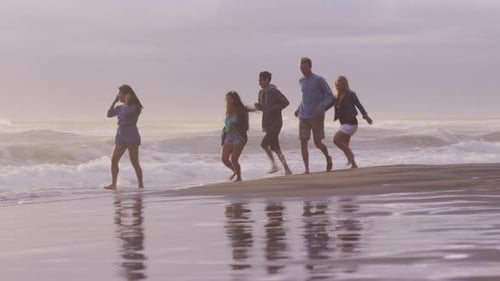 Group of friends at beach running in surf
