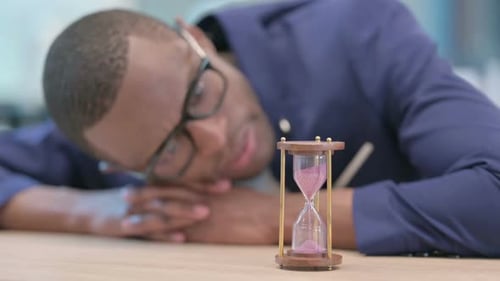 Man Resting with Hourglass on Desk