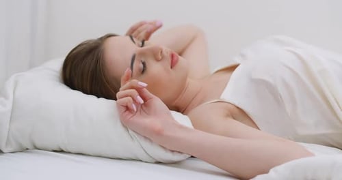 Young Female Sleeping in Bed, Waking Up in the Morning, Close-up of a Female Face, Woman Opens Her