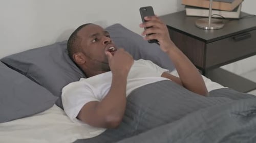 Surprised Man Using Phone Lying in Bed