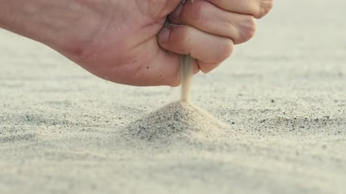 A Boy's Hand is Dropping a Pile of Sand From the Beach