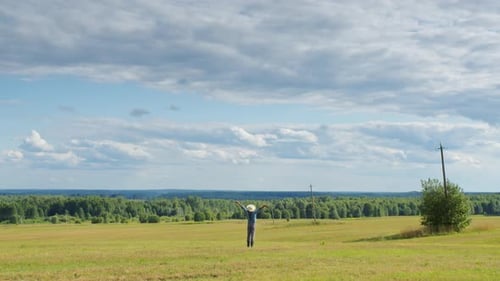 Farmer Standing in Mown Field Raising His Hands