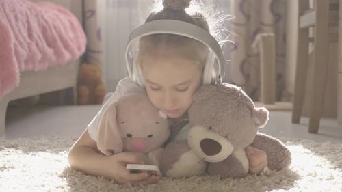 A School Girl Plays the Phone Lying on the Floor in Her Room, Along with Her Her Favorite Toys.
