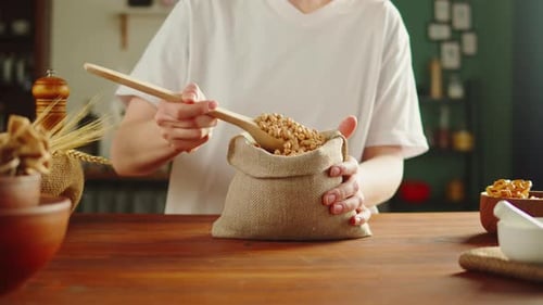 Person scoops dried chickpeas into burlap sack