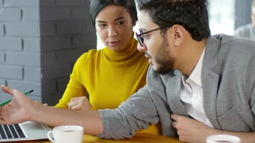 Coworkers Discussing Business Plan on Laptop at Cafe Table