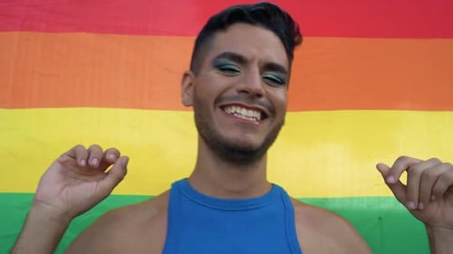 Smiling Young Adult in Front of Pride Flag