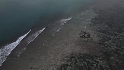 Aerial View of Waves Crashing on Dark Beach