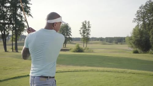 Man Swinging Golf Club on the Green Course