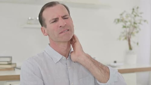 Man Massaging Stiff Neck in Home Setting