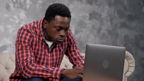 Young Adult Typing on Laptop While Sitting on Couch