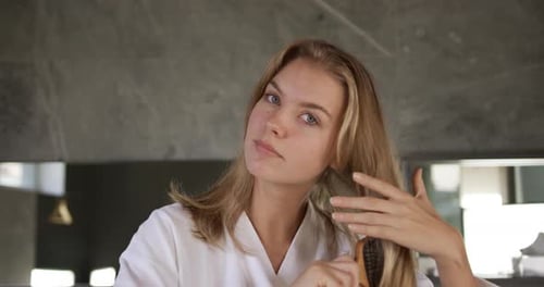 Front view of caucasian woman brushing hair in hotel