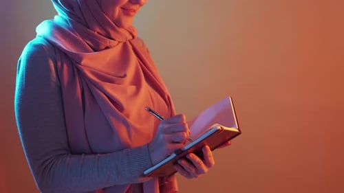 Woman Writes in Notebook with Orange and Blue Lighting