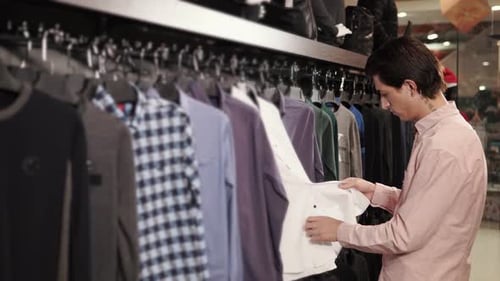 Comprador masculino está escolhendo uma camiseta em uma loja em um shopping center