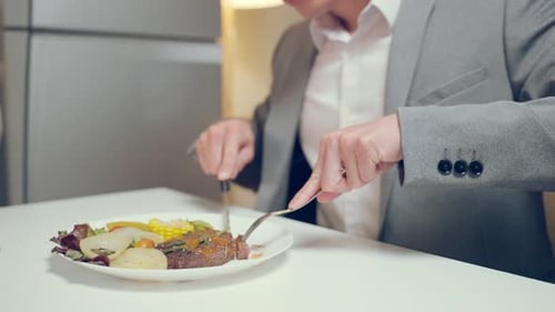 Young Adult in Suit Eats Steak Dinner