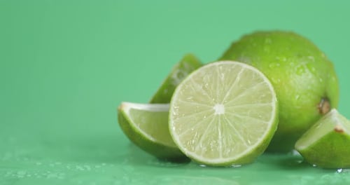 Fresh Limes with Water Droplets on Green