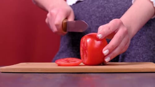 Woman Slicing a Fresh Tomato on Cutting Board