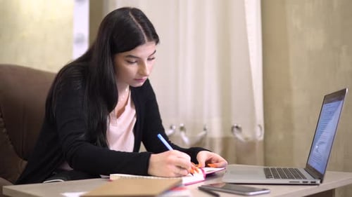 Woman Studies with Laptop and Notebook Indoors