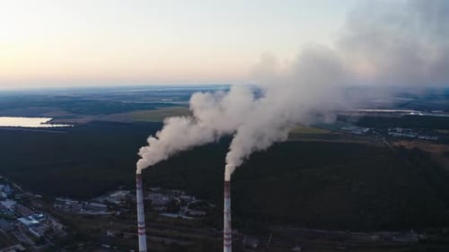 Power plant with white smoke over blue sky