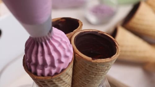 Eine Frau macht Marshmallows in Waffeltüten. Mit einem Gebäckbeutel