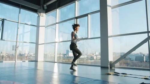Slow Motion of Slender Sportswoman Exercising with Jumping Rope in Modern Gym