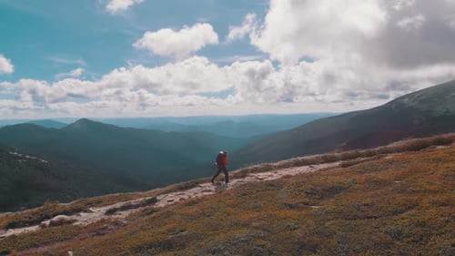 Vue aérienne d'un voyageur avec un sac à dos escaladant le versant d'une montagne. Tir épique
