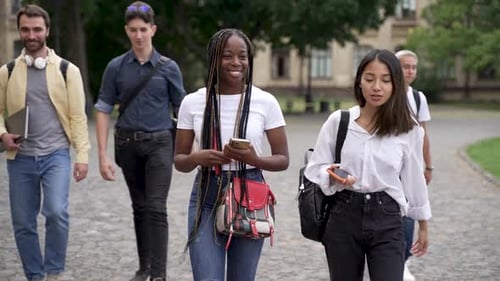 Positive gemischtrassige Studenten unterhalten sich während des Spaziergangs