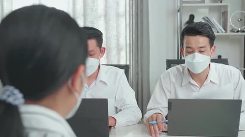 Employees Meeting at Desk Using Laptops