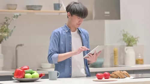 Young Adult Uses Tablet in Bright Kitchen