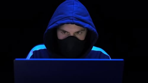 Hacker in Hood and Mask Writing Virus Program for Cyber Attack. Police Lights