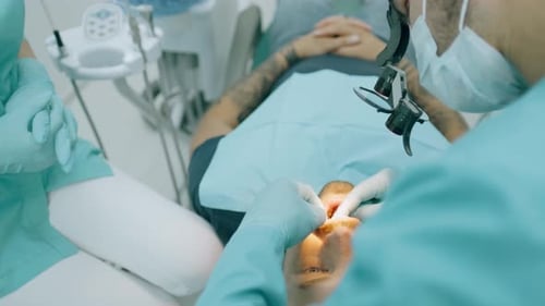 Dentist with Nurse and Patient in Dentist Office. A Patient Getting Dental Treatment at Dental