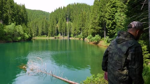 Man walking through the forest on the shore of the mountain lake. Mountain forest lake.