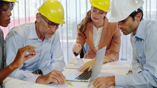 Architects Reviewing Blueprints Together Around Table