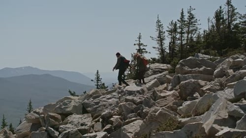 Hikers Climb Rocky Mountain Peak on Sunny Day