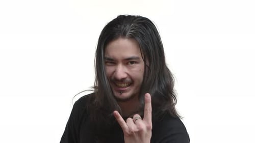 Nahaufnahme eines aufgeregten ostasiatischen Rockers mit langen dunklen Haaren und Piercing, das ein schweres Metallschild mit