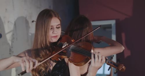 Women Playing Violins in an Indoor Setting
