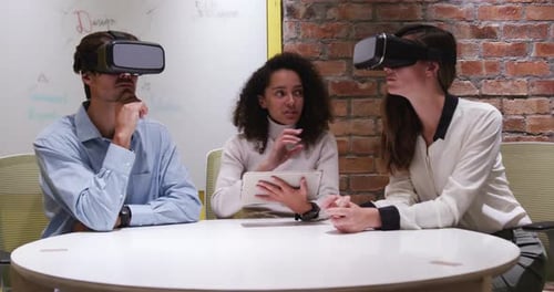 Creative businesspeople using virtual reality headset in modern office