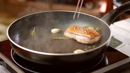 Duck Breast Frying in Pan with Herbs