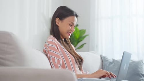 Smiling Woman Typing on Laptop at Home