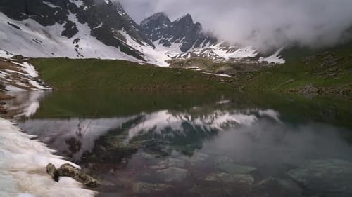 Timelapse of a Clear Lake Surrounded By Mountains. Clouds Are Billowing