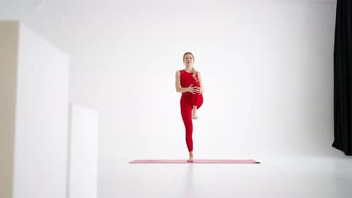 Schöne junge Frau in roter Sportbekleidung beim Yoga oder Pilates-Übungen auf weißem Hintergrund