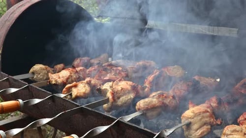 Köstliches Grillfleisch auf Metallspießen wird mit brennender Holzkohle gegrillt.