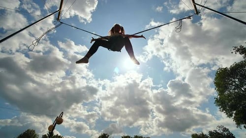 Teenage Girl Silhouette Jumping on the Trampoline Bungee Jumping. Slow Motion Video.
